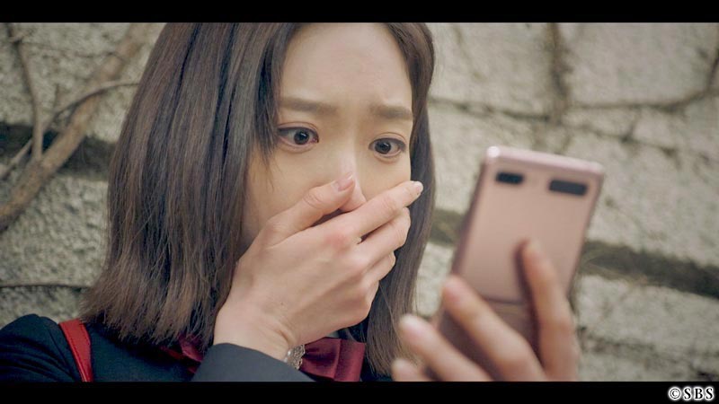 スマホを見て手をおさえる女性