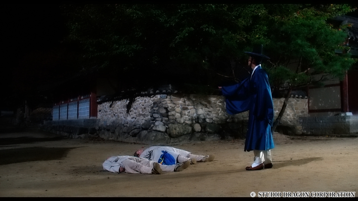 倒れている男性2人を見下ろす人