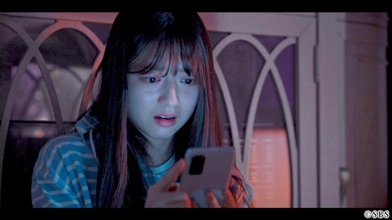 スマホの画面を見て驚く女性