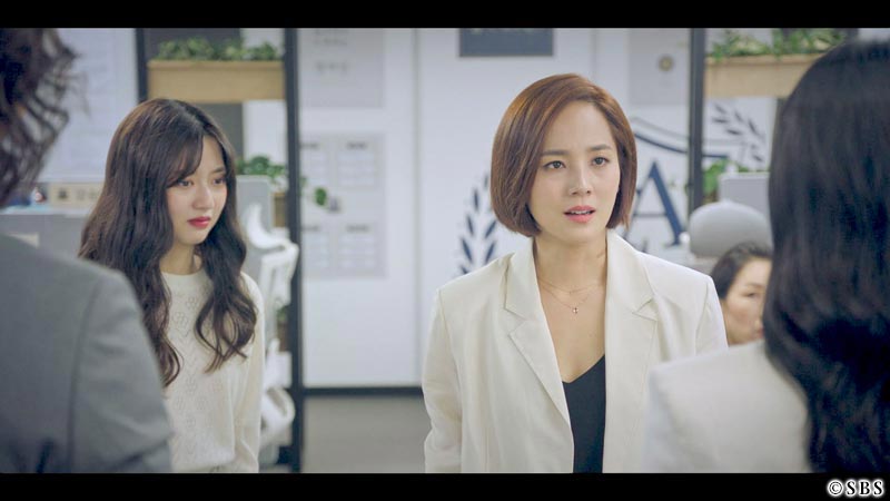 目の前の人と話す女性と、その後ろで悲しい顔をする女性