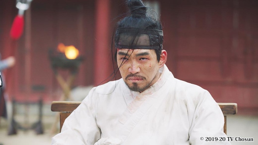 顔に血をつけにらむ男性