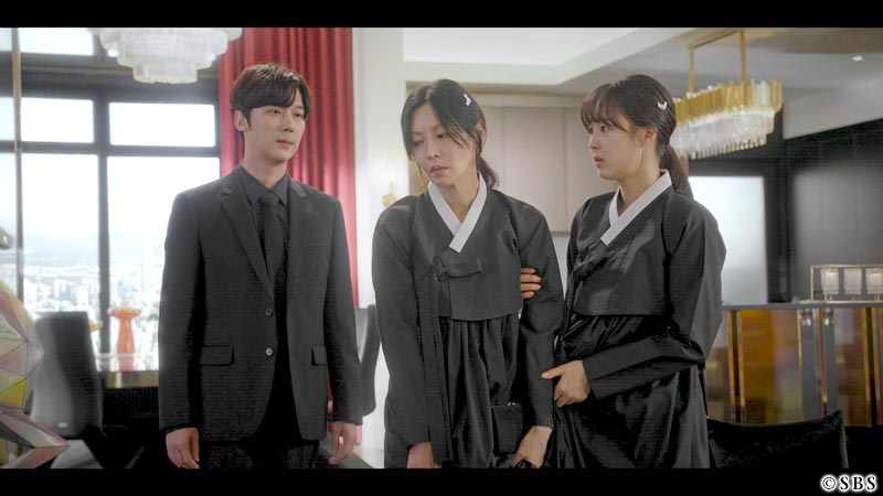 疲れた顔の女性、その女性の腕をつかむ女性、その様子を見る男性