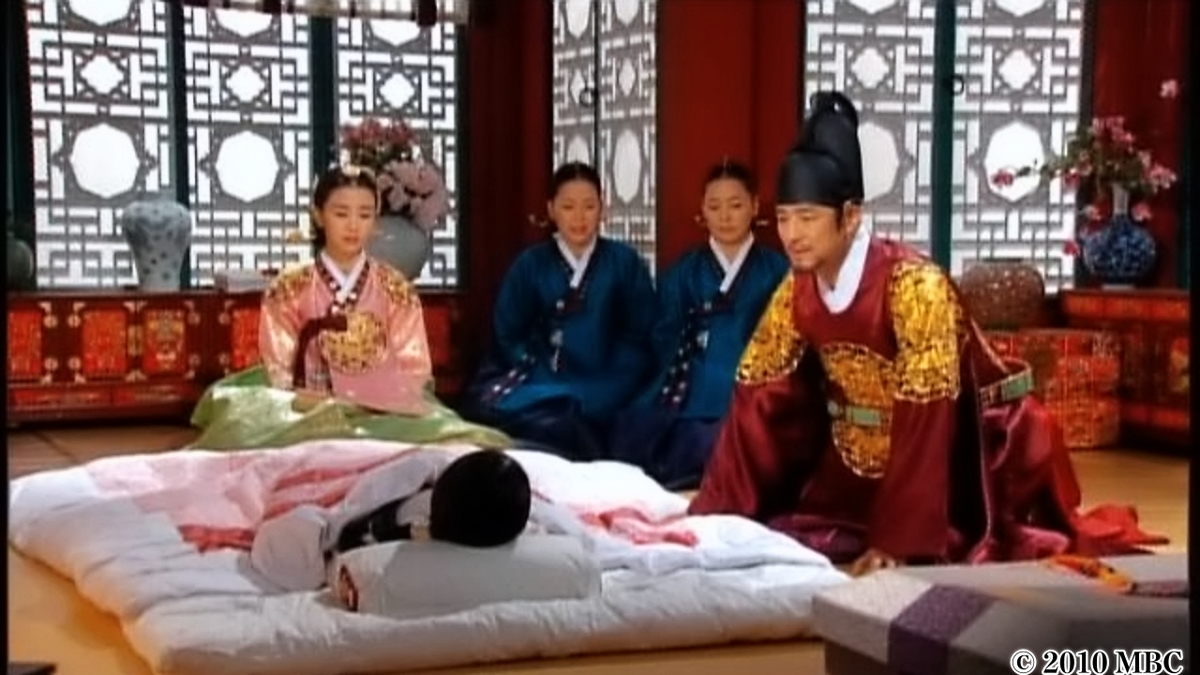 布団に寝ている女性に声をかける男性