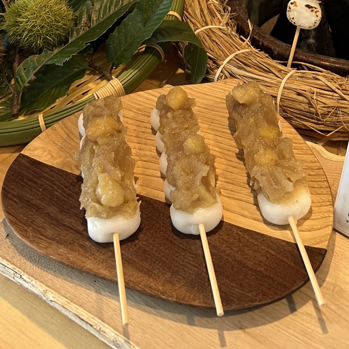 串に刺さったもちの上に栗のあんこがのっている