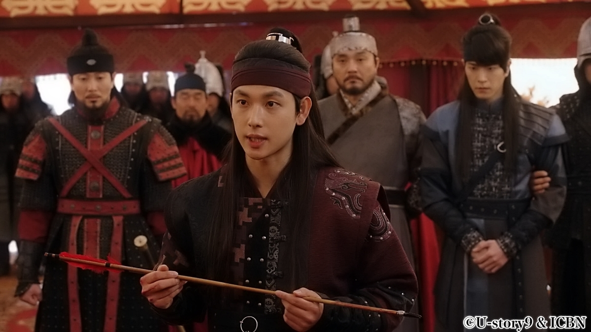 矢を持ちながら話す男性兵士　その後ろで見守る男性兵士たち