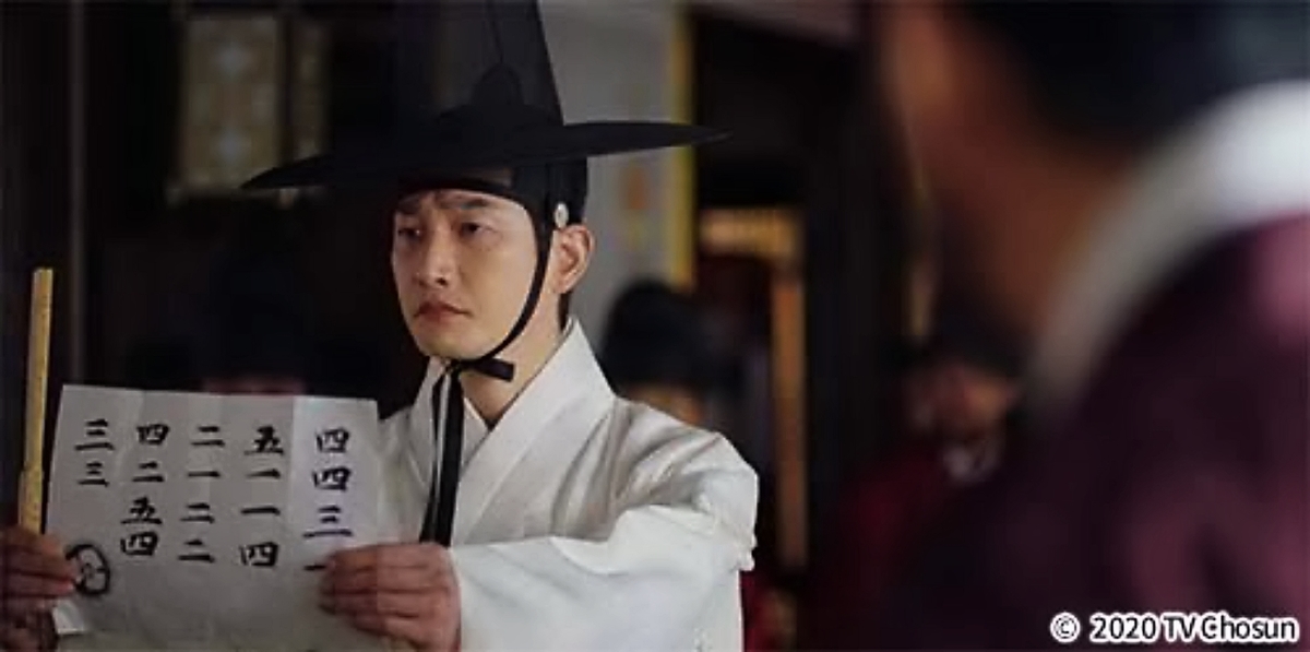 紙を広げて見せる男性