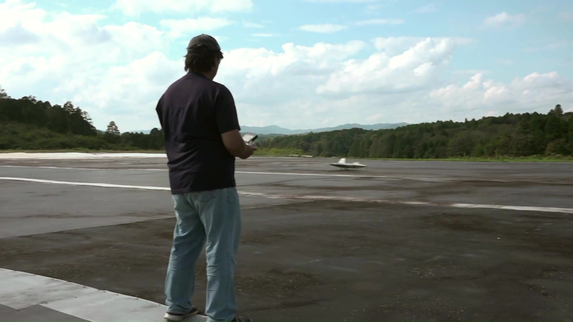 滑走路でラジコン飛行機を着陸させる男性
