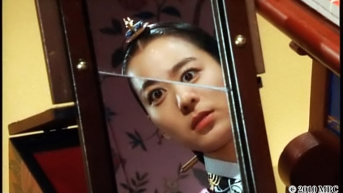 割れた鏡に女性が映っている