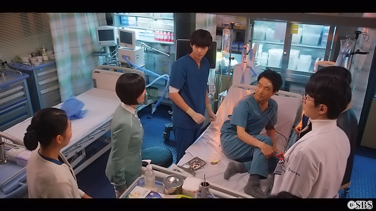 ベットから起き上がる医師と彼を囲うスタッフたち