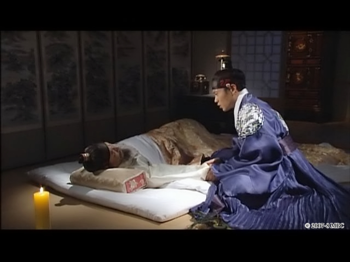 床に臥す男性に話かけている人