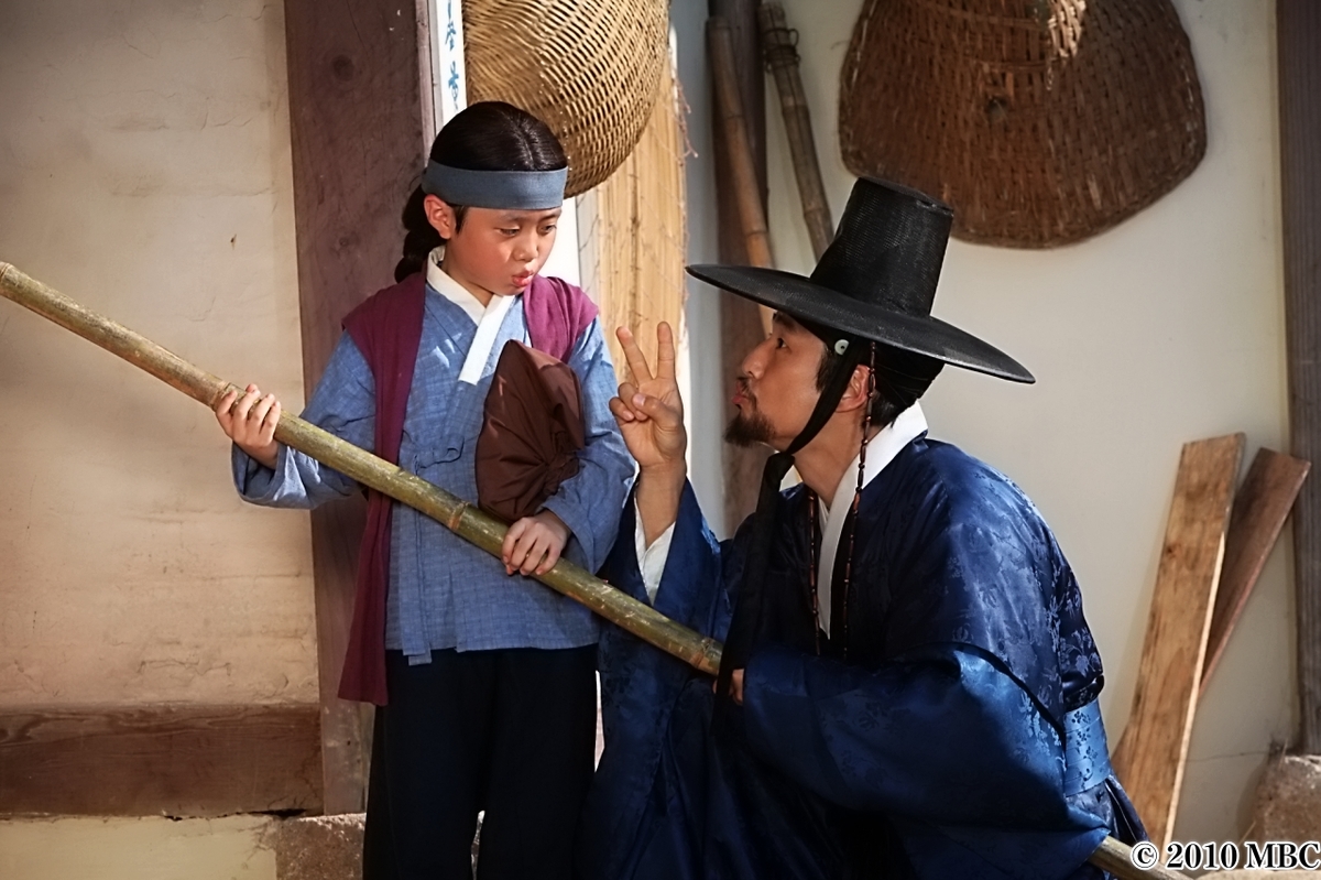 棒をもった子供に話しかける男性