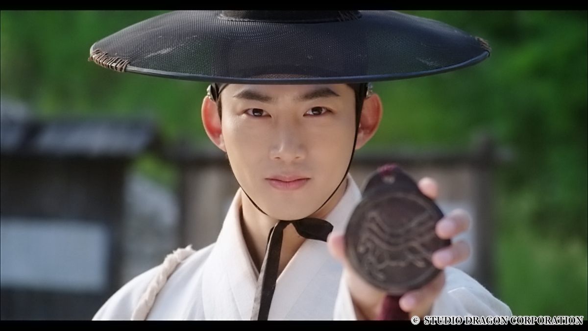 紋章を見せる男性