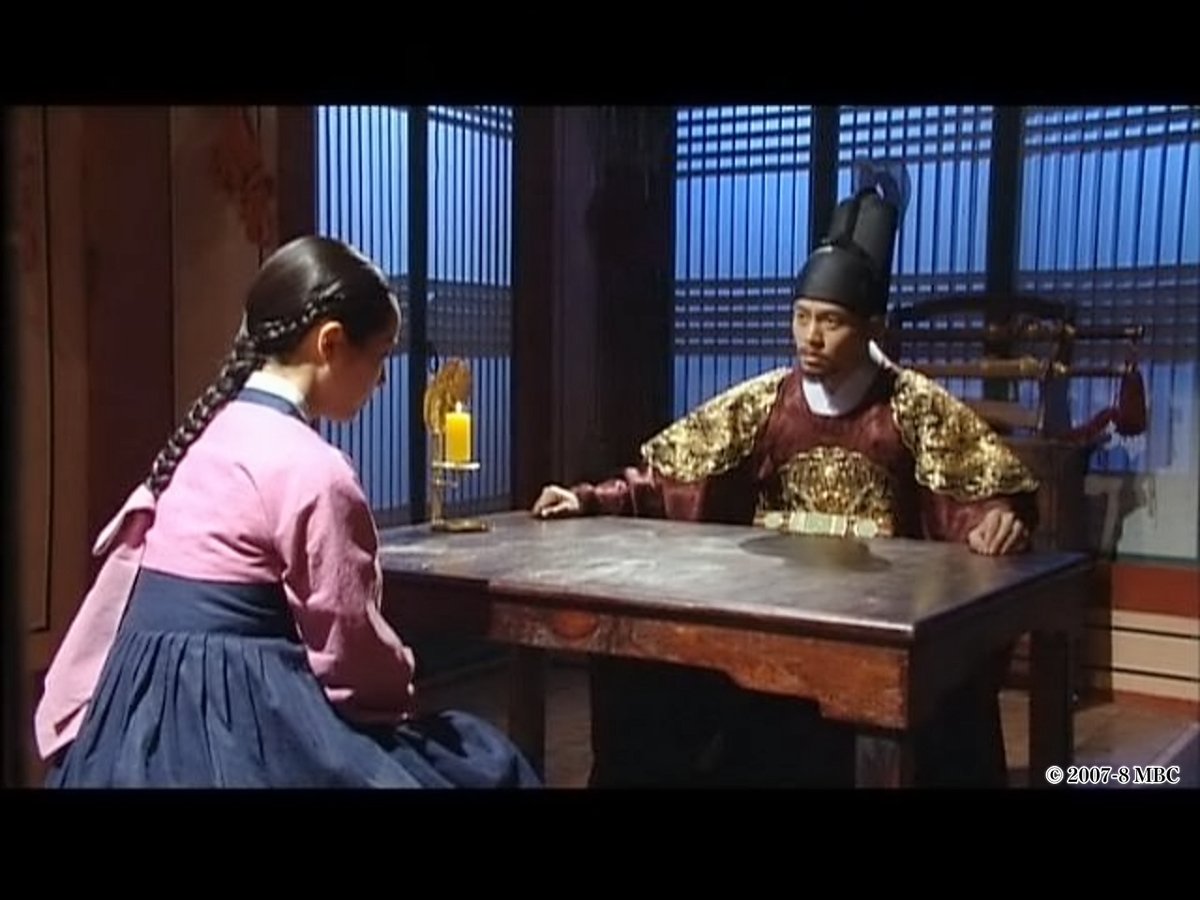 机を挟んで話す男女