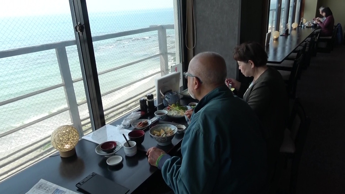 窓の外の海を眺めながら料理を楽しんでいる様子