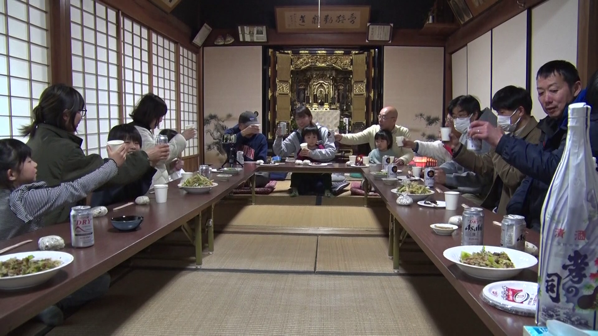 大勢が座り、乾杯のためのドリンクを手に持つ様子